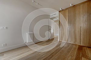 Access hallway to a bedroom with built-in wardrobes with custom-made light oak doors, white painted walls, white shelves on the