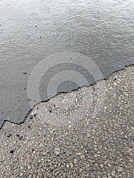 Access road with deteriorating asphalt, gravel, and rainwater accumulation in Wales