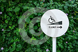 Accessibility in city public park, Sign board of Ramp for Disabled people or handicapped, Natural green leaf as backdrop wall