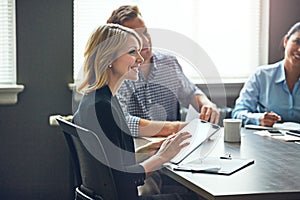 Accessing her files from inside the boardroom with wireless technology. a businesswoman using a digital tablet during a