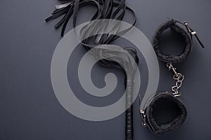 Accessories for bdsm on a black background. Leather lash and leather handcuffs. Valentine`s Day. Erotic shop. Copy space