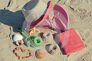 Accessories and children toys for playing or relax on sand at beach. Straw hat, flip flop and towel. Summer time