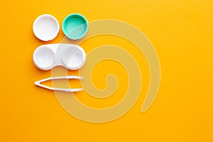 Accessories for contact lenses: a solution container, tweezers. Yellow background