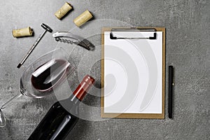 Accessories for oenology. Cup with wine on concrete background and notepad. Copy Space