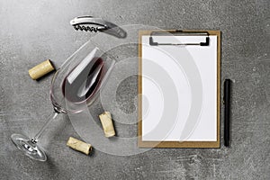 Accessories for oenology. Cup with wine on concrete background and notepad. Copy Space