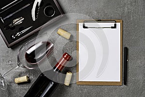 Accessories for oenology. Cup with wine on concrete background and notepad. Copy Space