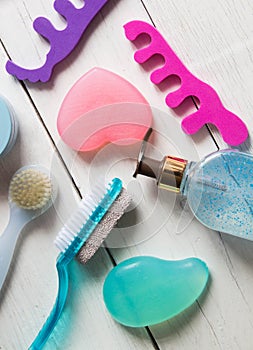 Accessories and products for foot care. Epilator, brush, pumice, soap, gel, toe separator on a white background. Top view