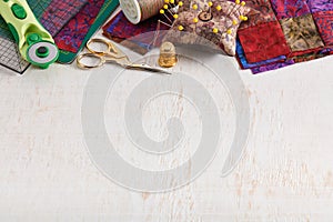 Accessories for quilting on white wooden surface on the upper part of the image, space for text