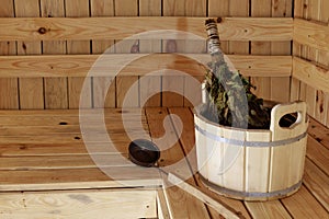 Accessories for the sauna in the wooden sauna. Wooden tub, birch broom in hot steam. Finnish bath