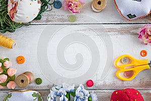 Accessories for sewing lie on a white background. Scissor, pin cushion, button, coil and artificial flowers. Copy space