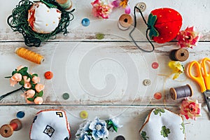 Accessories for sewing lie on a white background. Scissor, pin cushion, button, coil and artificial flowers. View from the top