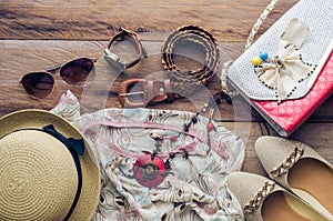 Accessories for teenage girl on her vacation, hat, stylish for summer sunglasses, leather bag, shoes and costume on wooden floor