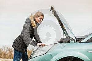 Blonde woman and broken down car on road