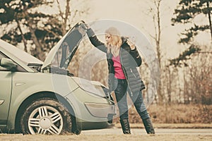 Blonde woman and broken down car on road