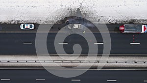 Accident - burned out car on the edge of the motorway in winter, aerial view.