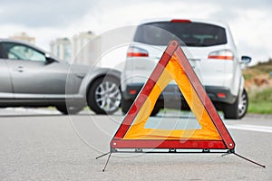 Accident or crash with two automobile. Road warning triangle sign in focus