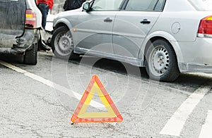 Accident or crash with two automobile. Road warning triangle sign in focus