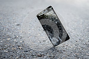 Accident with gadget concept. Device need repairing. Copy space. Mobile phone falling and crashes on asphalt, broken smartphone