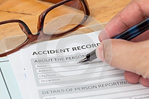 Accident report application form and human hand with pen on brow