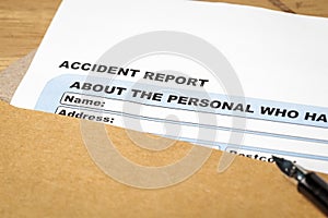 Accident report application form and pen on brown envelope, business insurance and risk concept; document is mock-up