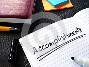 Accomplishments list in the notebook on the desk.