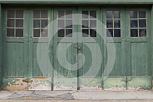 Accordian fold green painted weathered garage doors with windows, creative copy space