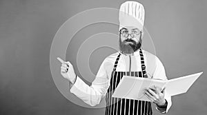 According to recipe. Man bearded chef cooking food. Culinary arts concept. Amateur cook read book recipes. Man learn