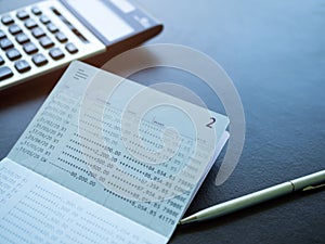 Account book bank with calculator and pen on woonden background.