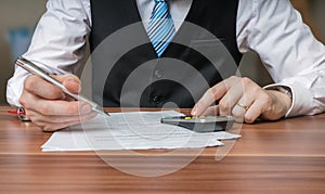Accountant or business man is calculating taxes with calculator photo