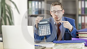 Accountant businessman at his desk in the office shows a finger on a calculator. Financial check. Preparation of a report by an