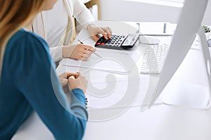 Accountant checking financial statement or counting by calculator income for tax form, hands close-up. Business woman