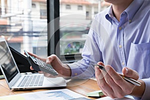 accountant counting with calculator at office. businessman analyze income & budget at workplace. financial advisor calculating ta