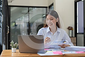 Accountant hand holding pen working on calculator to calculate business data, accountancy document and laptop computer