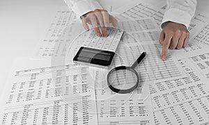 Accountant holding a calculator pointing at numbers on financial documents. Ð¡oncept of finance, search and accounting