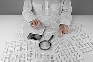 Accountant holding a calculator pointing at numbers on financial documents. Ð¡oncept of finance, search and accounting