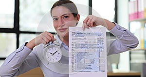 Accountant holds 1040 personal income tax return and alarm clock