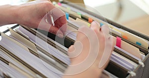 Accountant manager sorts folders in a paper drawer
