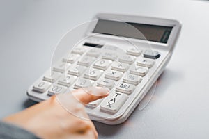 Accountant pressing tax button on calculator to calculate annual tax return