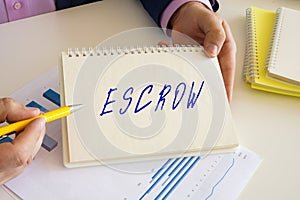 Accountant shows to the sign ESCROW sign on the writing-pad