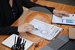 Accountant using calculator and analyzing financial graph reports on office desk.
