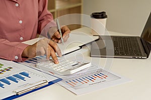 Accountant using computer with clamp and graph document, business man working on desk using calculator to calculate numbers, finan