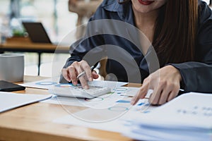 Accountant woman working on desk office with using a calculator to calculate the numbers, finance accounting concept