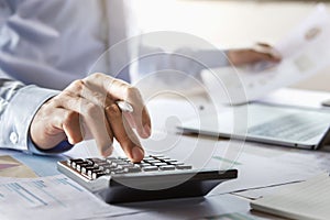 accountant working on desk using calculator for calculate finance report in office