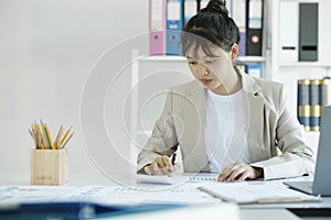 Accountant is working on her desk by using her calculator.