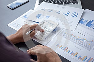 Accounting businessmen are calculating company income tax with calculators and graphs on the desks