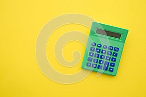 Accounting, tax, banking, business and financial concept. Flat lay or top view of green calculator on yellow table background