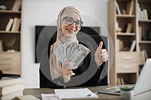 Accounting, taxes and finances concept - young confident muslim woman with papers counting money