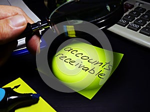 Accounts receivable. Accountant looks through magnifying glass on a paper