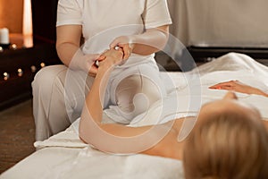 Accurate masseuse in white costume being focused on hands