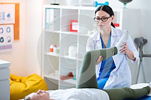 Accurate professional nurse moving problematic leg of little girl